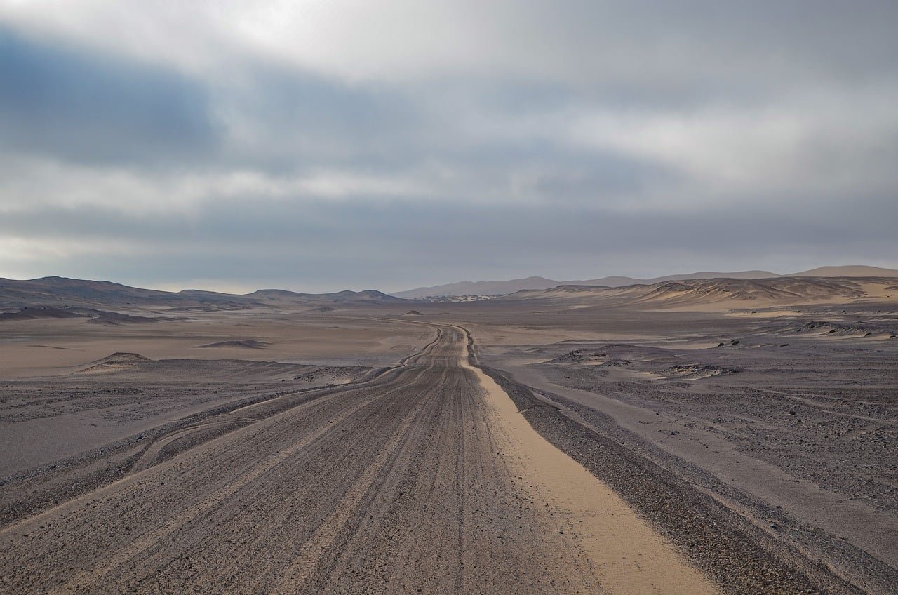 namibia, desert road, gravel road, tire tracks, clouded sky, sand landscape, rock landscape, lonliness, long-distance travel, wilderness, expanse, adventure, offroad, nature, steppe, dry landscape, horizon, isolation, vehicle lane, barren landscape