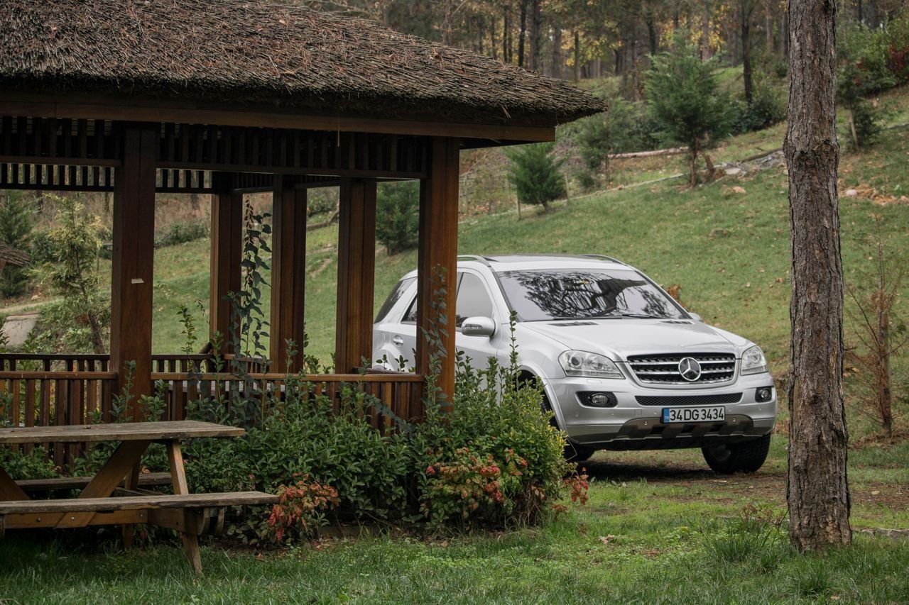 A luxury SUV parked next to a wooden gazebo in a lush green park setting, İstanbul.