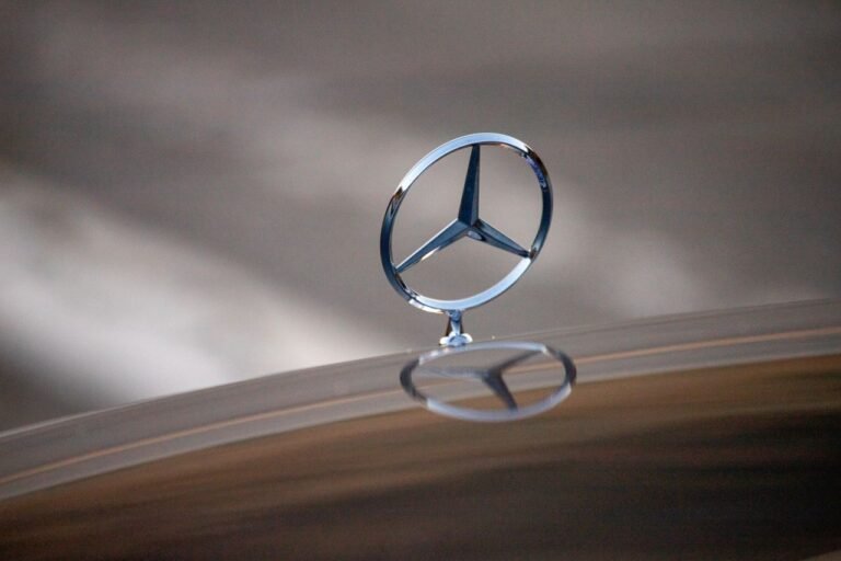 Sleek Mercedes-Benz logo reflection on a car hood, showcasing luxury design.
