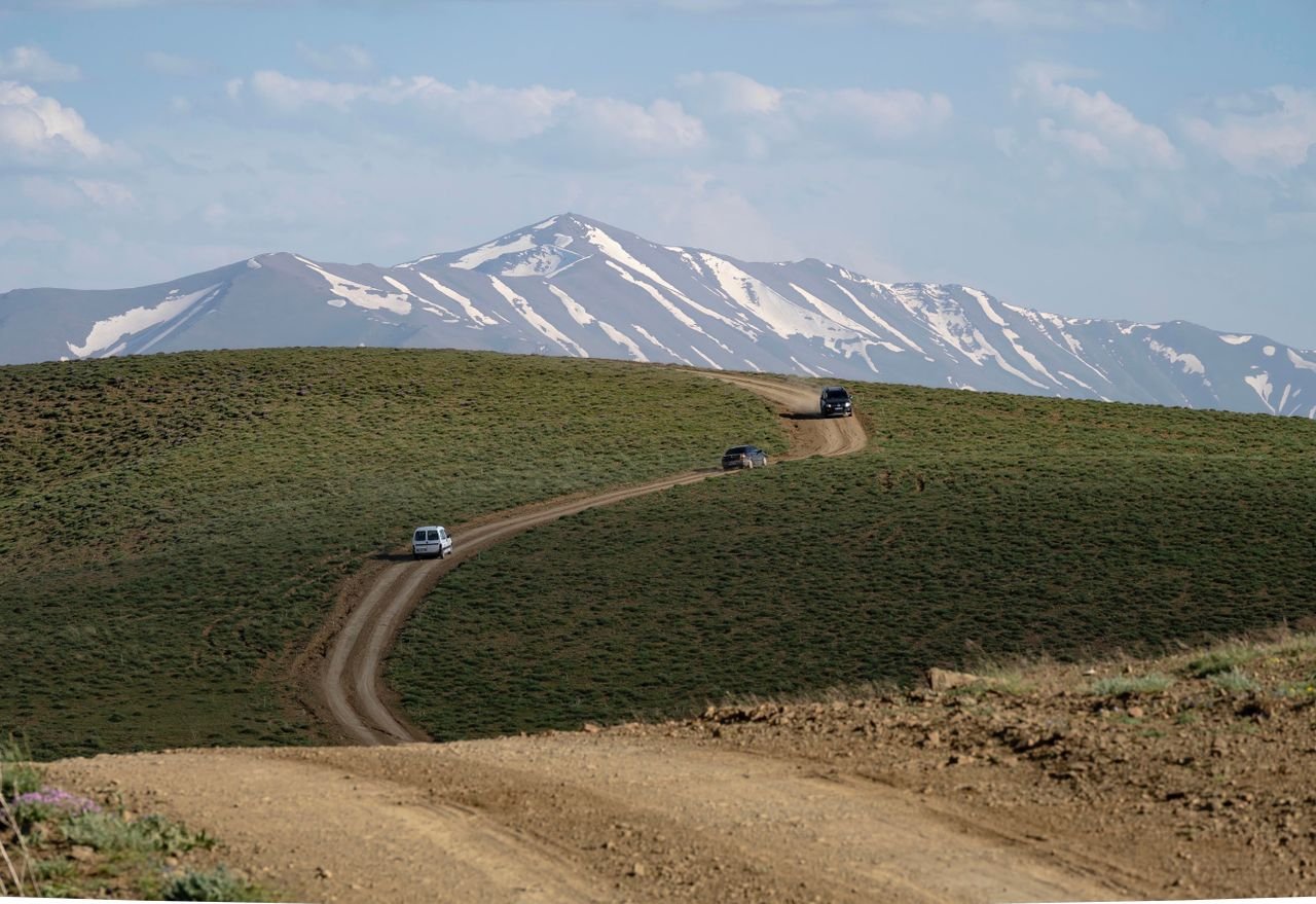 Capture of a dirt road leading through a stunning mountainous landscape with snow-capped peaks.