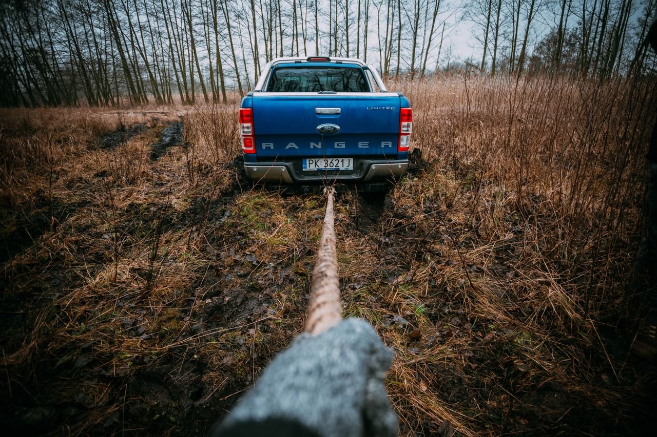 A blue Ford Ranger being pulled through a muddy field, showcasing off-road capabilities.
