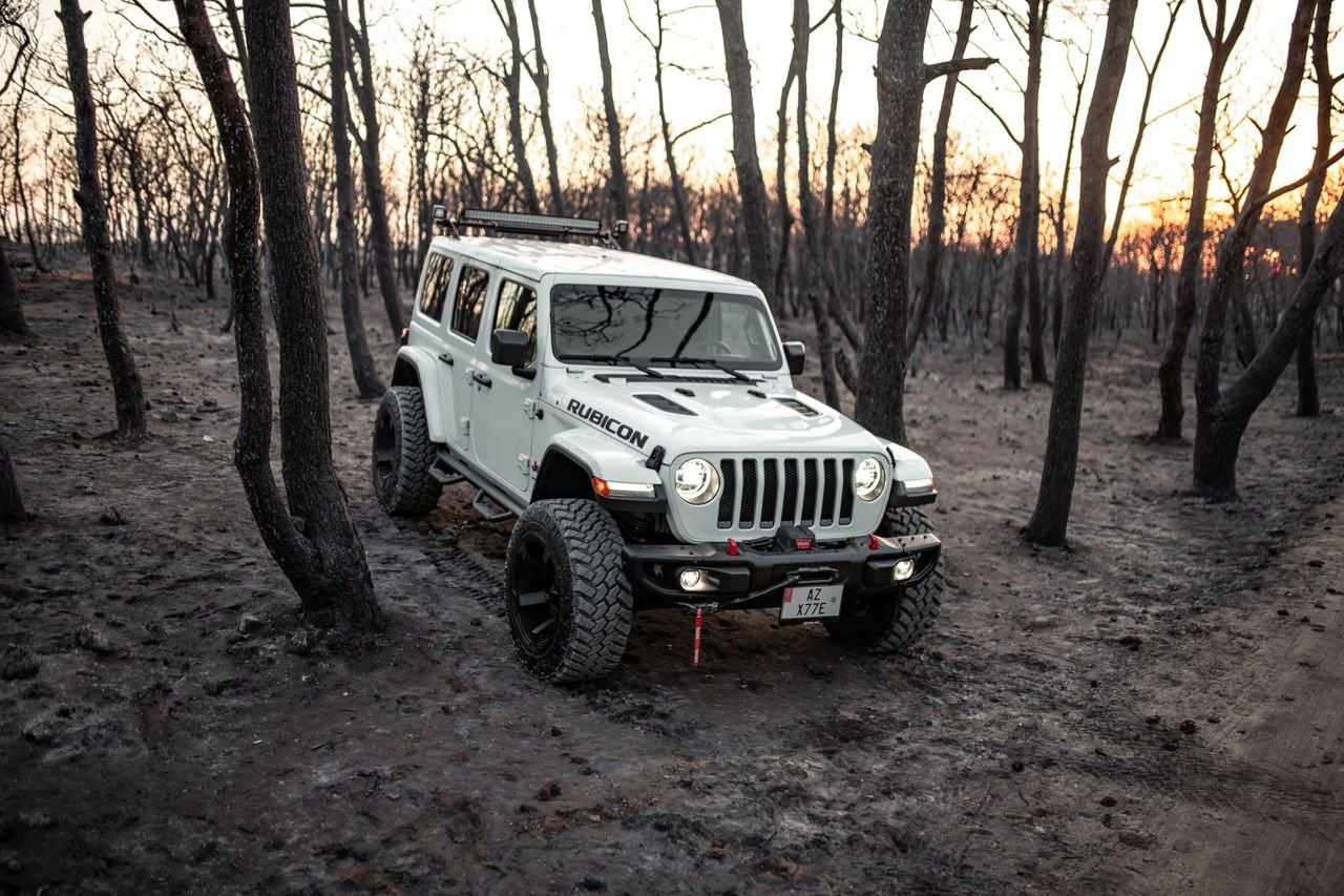 A rugged 4x4 vehicle navigating a bare forest landscape at sunset, ideal for off-road enthusiasts.