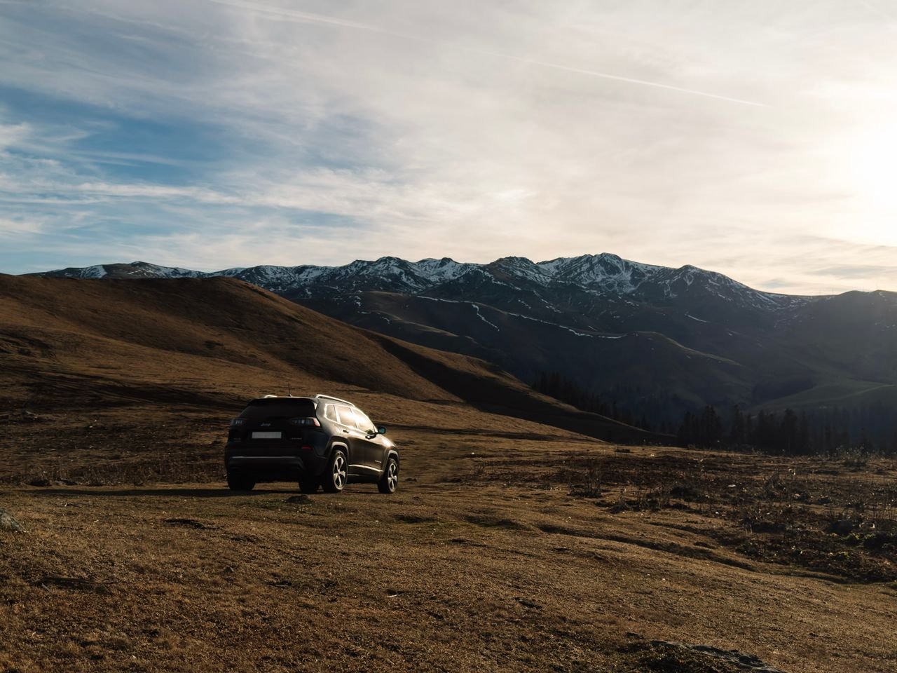 A stunning view of the Georgian mountains in Bakhmaro with an SUV under a beautiful sky.