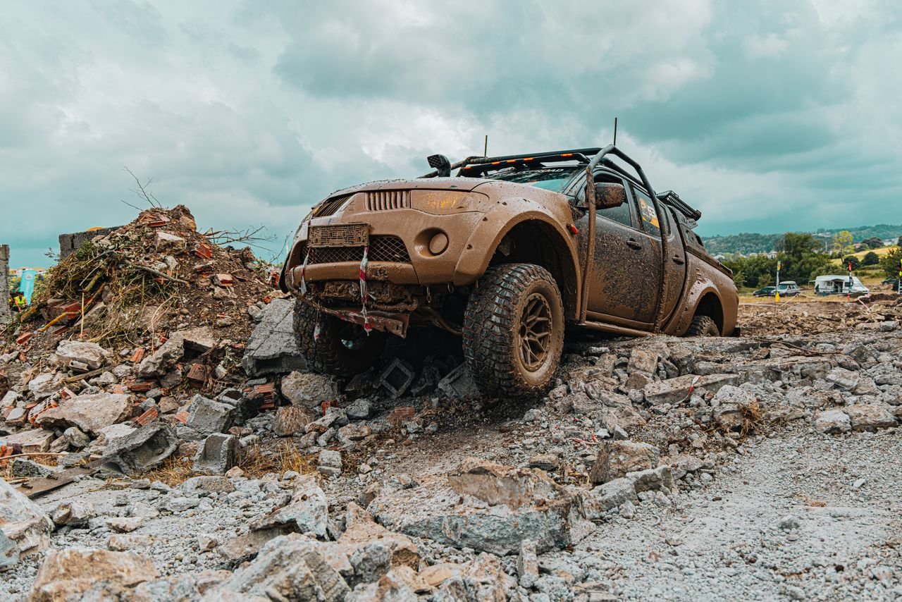A rugged offroad vehicle traverses rocky terrain, showcasing its durability in an outdoor race setting.
