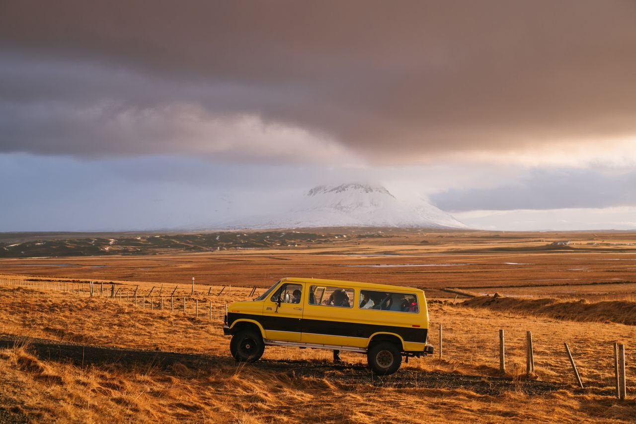 Explore the open road with a yellow van set against a vast countryside and distant mountain.