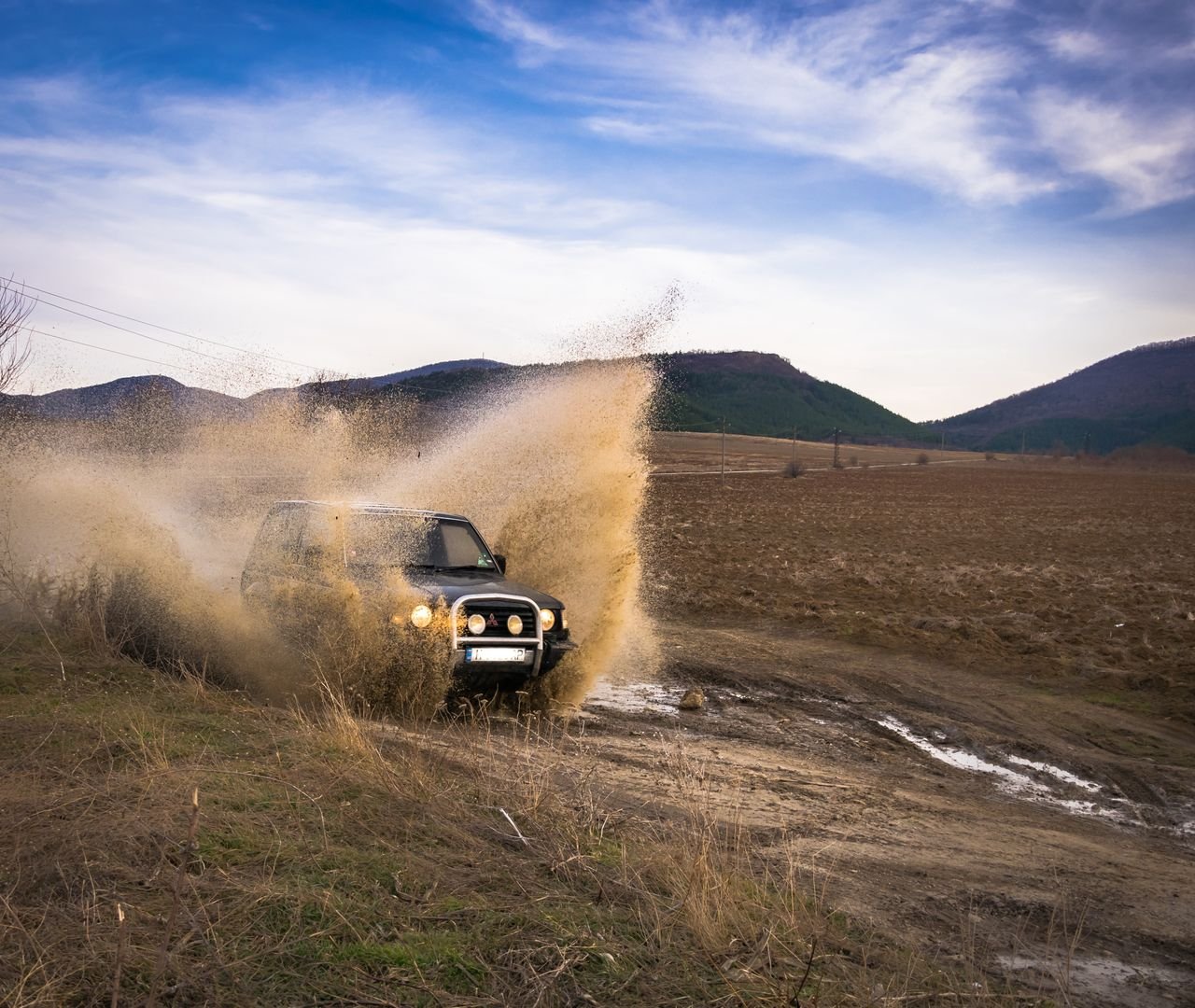 An SUV splashes through mud offroad in Veliki Preslav, Bulgaria, showcasing adventure and thrill.