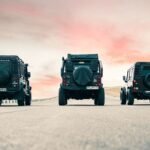 Three Land Rover vehicles parked on an open road with a beautiful sunset sky in Mashhad, Iran.