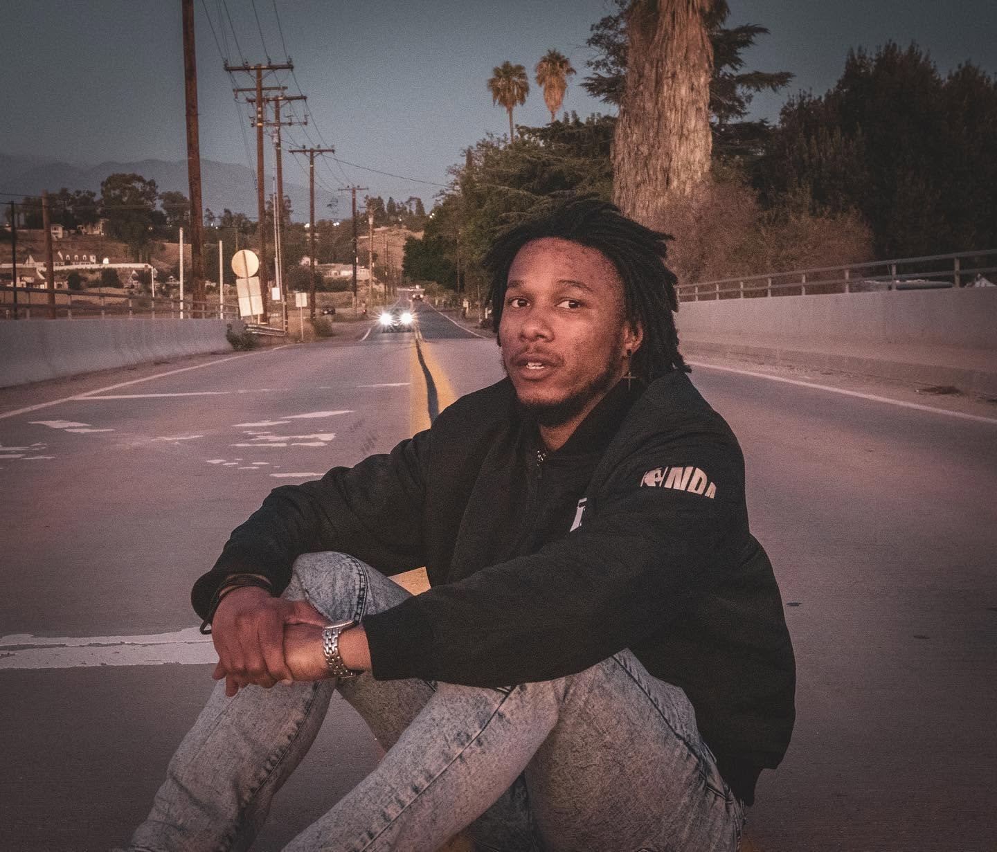 Man sitting in the middle of the street with car coming