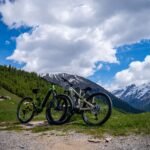 Parked mountain bikes under a blue sky with the snowcapped Alps in Livigno, perfect for summer adventures.