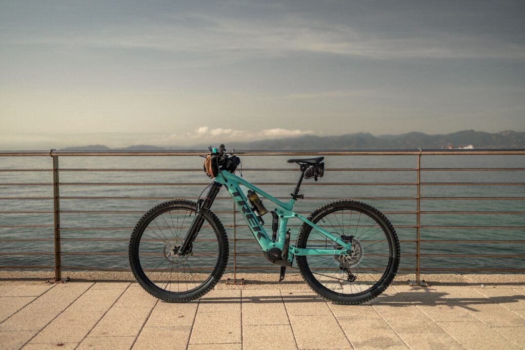 A mountain bike rests by the tranquil Sardinian seaside, perfect for adventure travel.